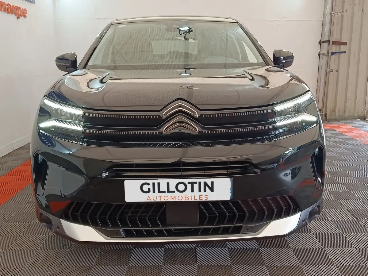 Vue avant d'un Citroën C5 Aircross noir 2024 avec calandre distinctive et phares LED allumés.