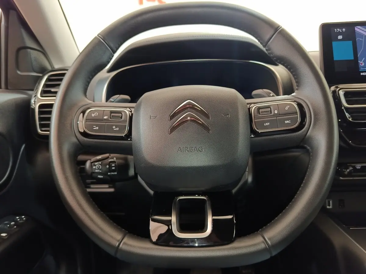 Vue centrée sur le volant cuir noir du Citroën C5 Aircross 2024 avec commandes multifonctions et tableau de bord numérique.