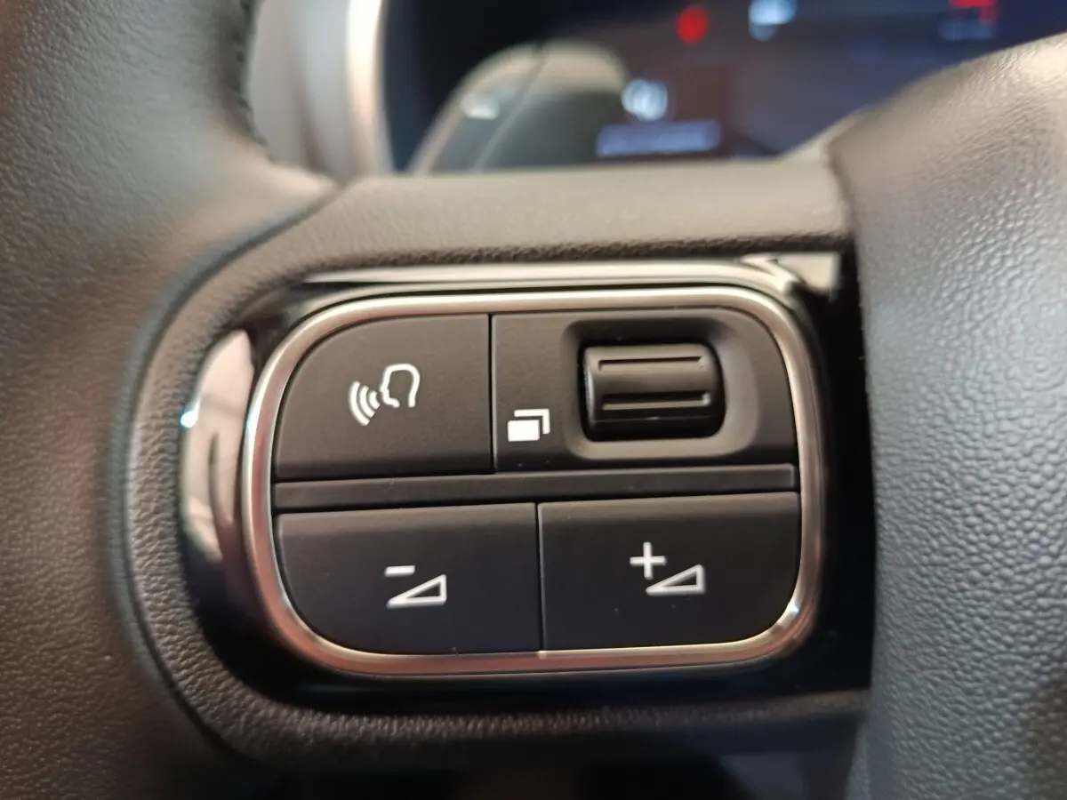 Gros plan sur les commandes vocales et volume au volant cuir noir du Citroën C5 Aircross 2024.