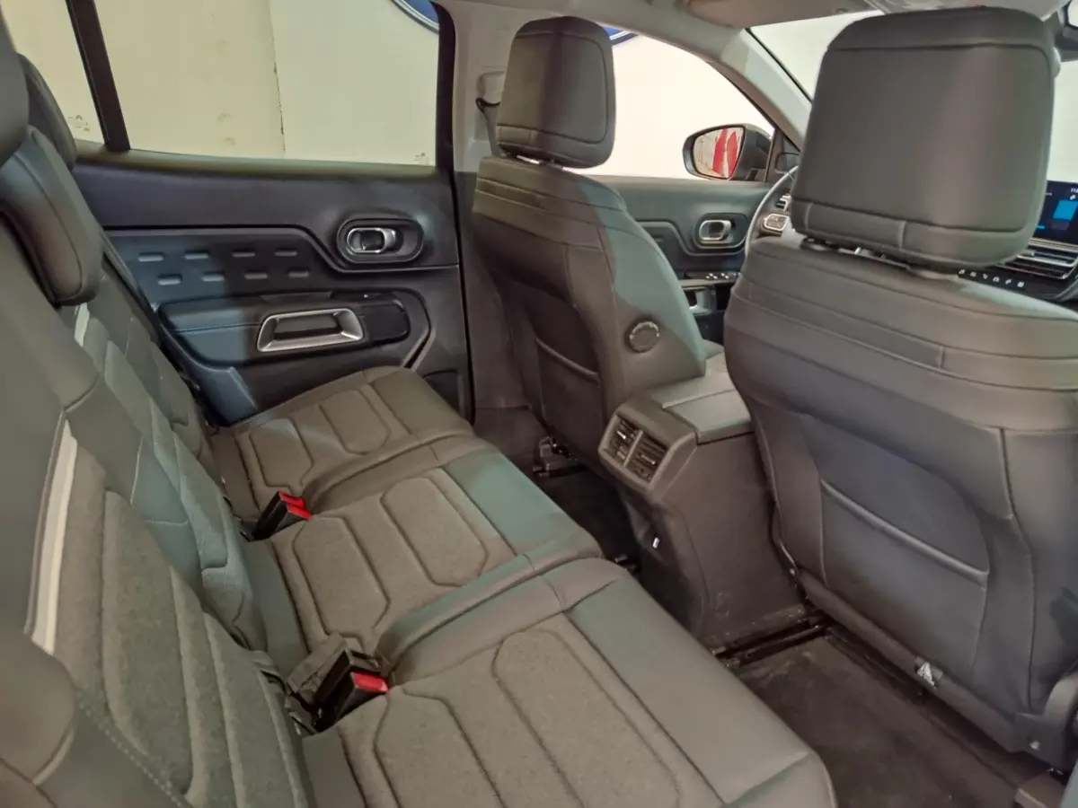 Vue intérieure arrière côté gauche du Citroën C5 Aircross 2024 noir, montrant les sièges en tissu et cuir avec aérateurs centraux.