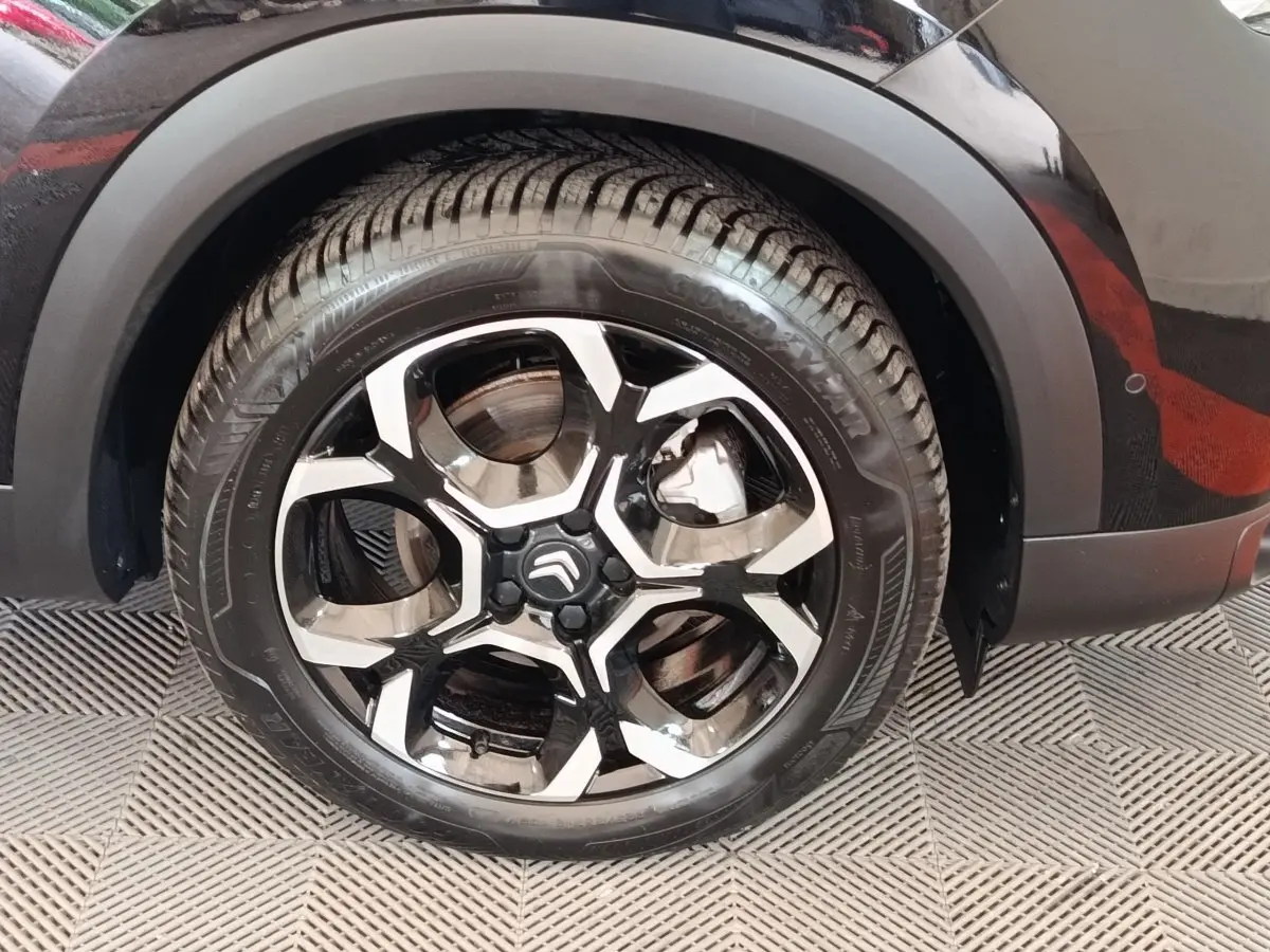 Gros plan sur la roue arrière droite noire du Citroën C5 Aircross 2024 avec jante alliage bicolore distinctive.