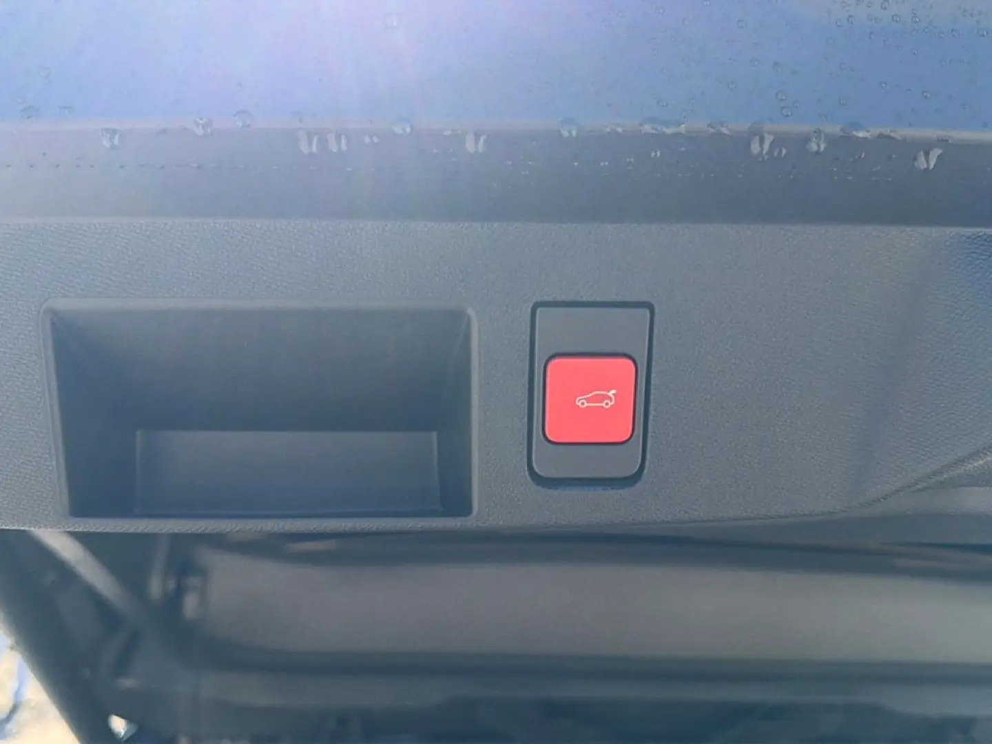 Bouton rouge d'ouverture électrique du hayon sur le bord intérieur du coffre d'un Citroën C5 Aircross blanc.