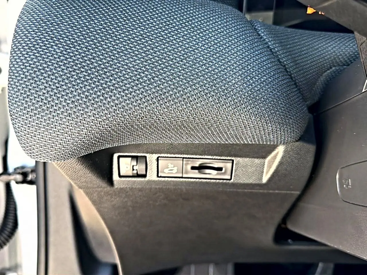 Gros plan sur les commandes de réglage lombaire du siège conducteur en tissu gris du Citroën C5 Aircross hybride 2026.
