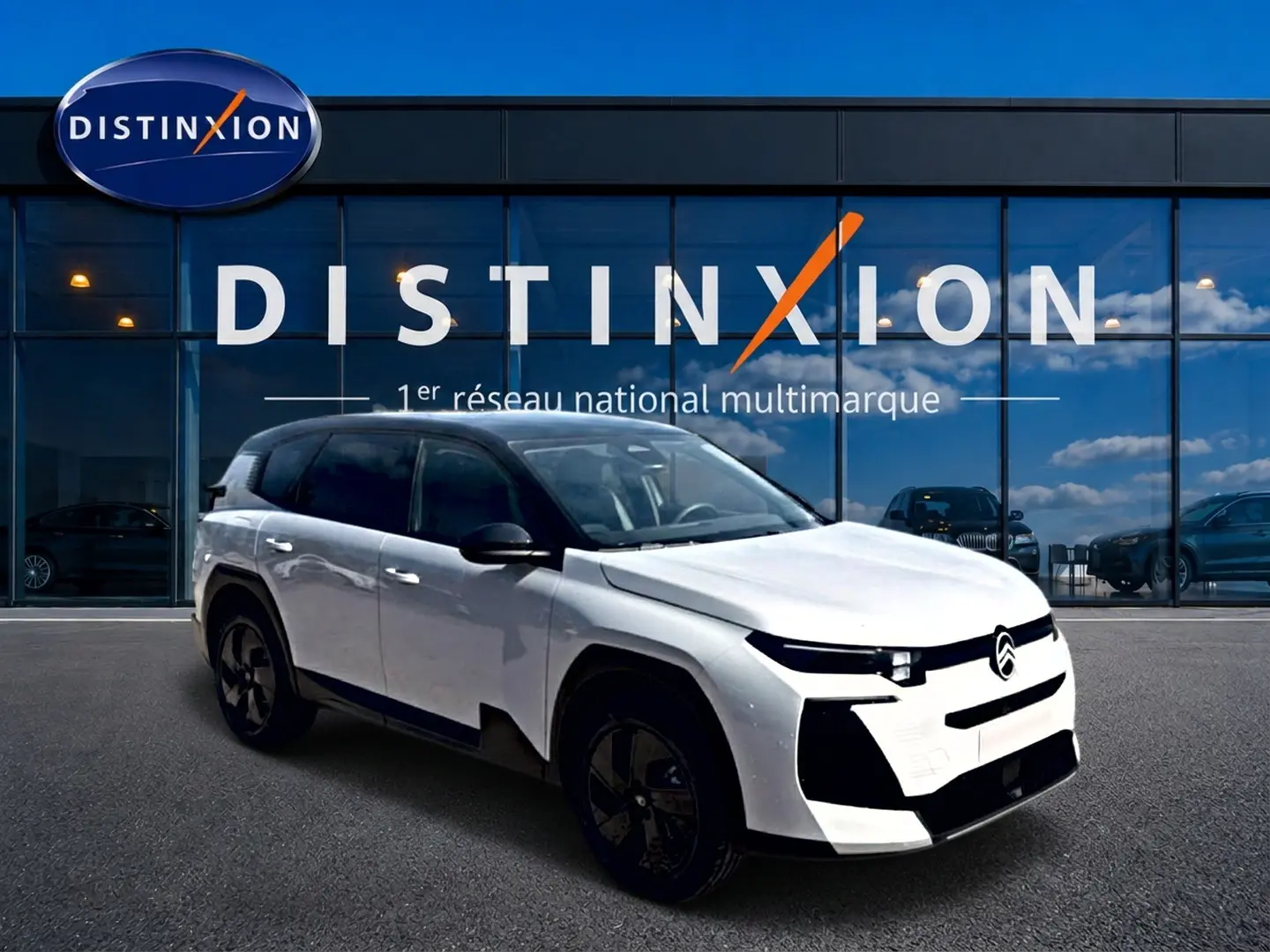 Vue 3/4 avant d'un Citroën C5 Aircross blanc à toit noir, avec jantes alliage noires, devant une vitrine Distinxion.