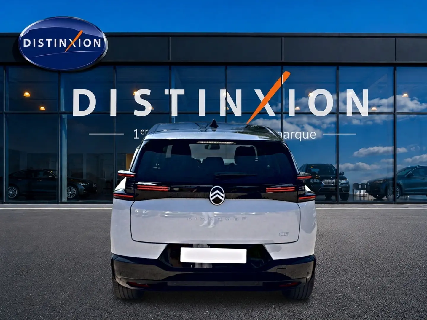 Vue arrière d'un Citroën C5 Aircross blanc et noir avec feux arrière LED, garé devant une vitrine Distinxion.