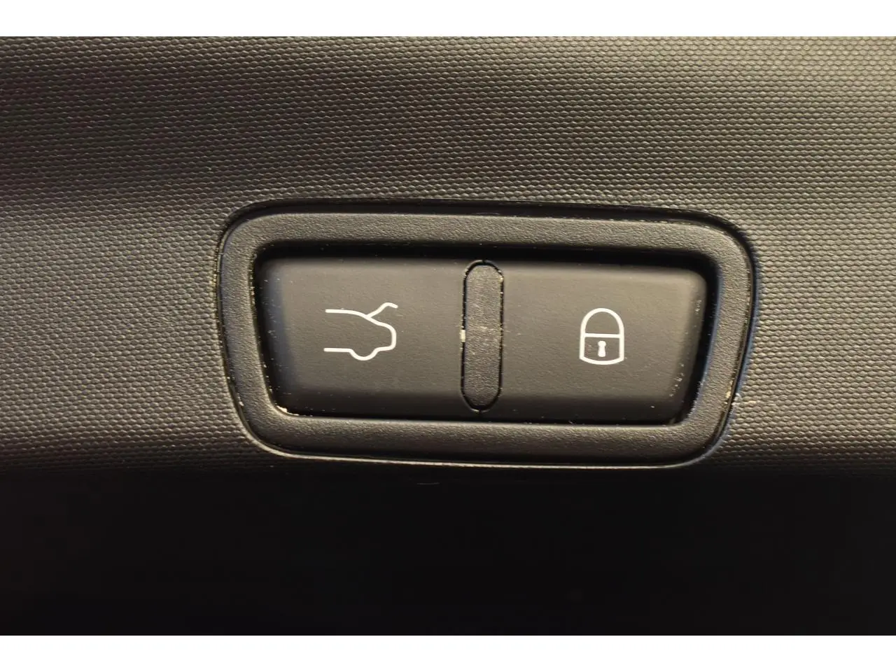 Gros plan sur les boutons d'ouverture du coffre et de verrouillage dans l'habitacle de l'Alfa Romeo Stelvio gris Vesuvio.