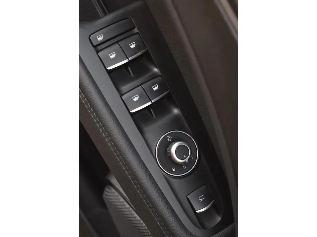 Gros plan sur les commandes des vitres et rétroviseurs côté conducteur de l'Alfa Romeo Stelvio 2024, intérieur noir.