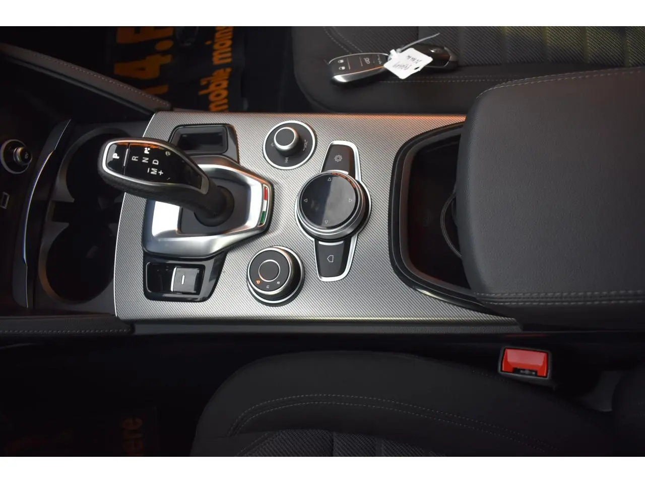 Vue rapprochée de la console centrale de l'Alfa Romeo Stelvio 2024, avec levier de vitesse et commandes circulaires.