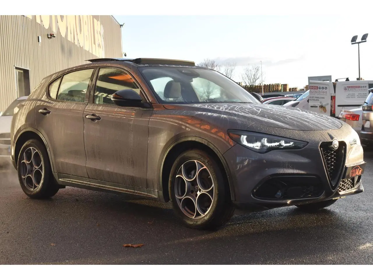 Alfa Romeo Stelvio gris Vesuvio en 3/4 avant droit, avec jantes 19'' Competizione et toit panoramique ouvert.