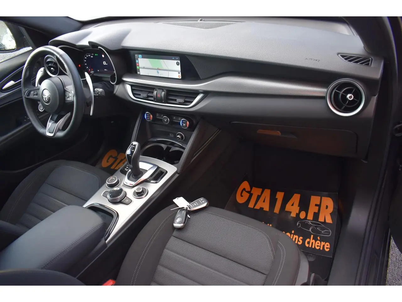 Intérieur de l'Alfa Romeo Stelvio 2024 vu côté conducteur, tableau de bord moderne avec écran tactile et volant sport.