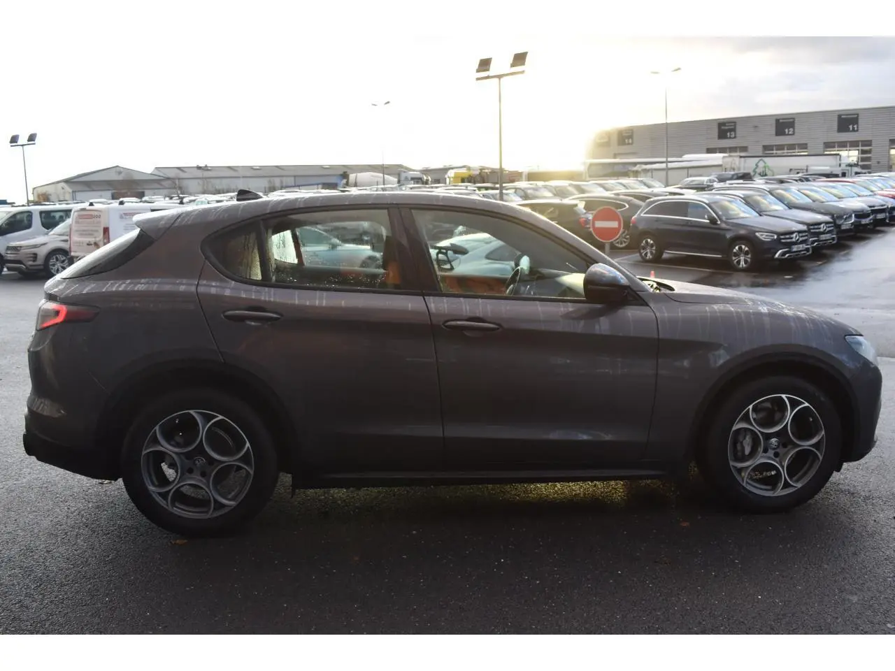 Profil côté gauche de l'Alfa Romeo Stelvio 2024 gris Vesuvio avec jantes 19'' Competizione et toit panoramique visible.