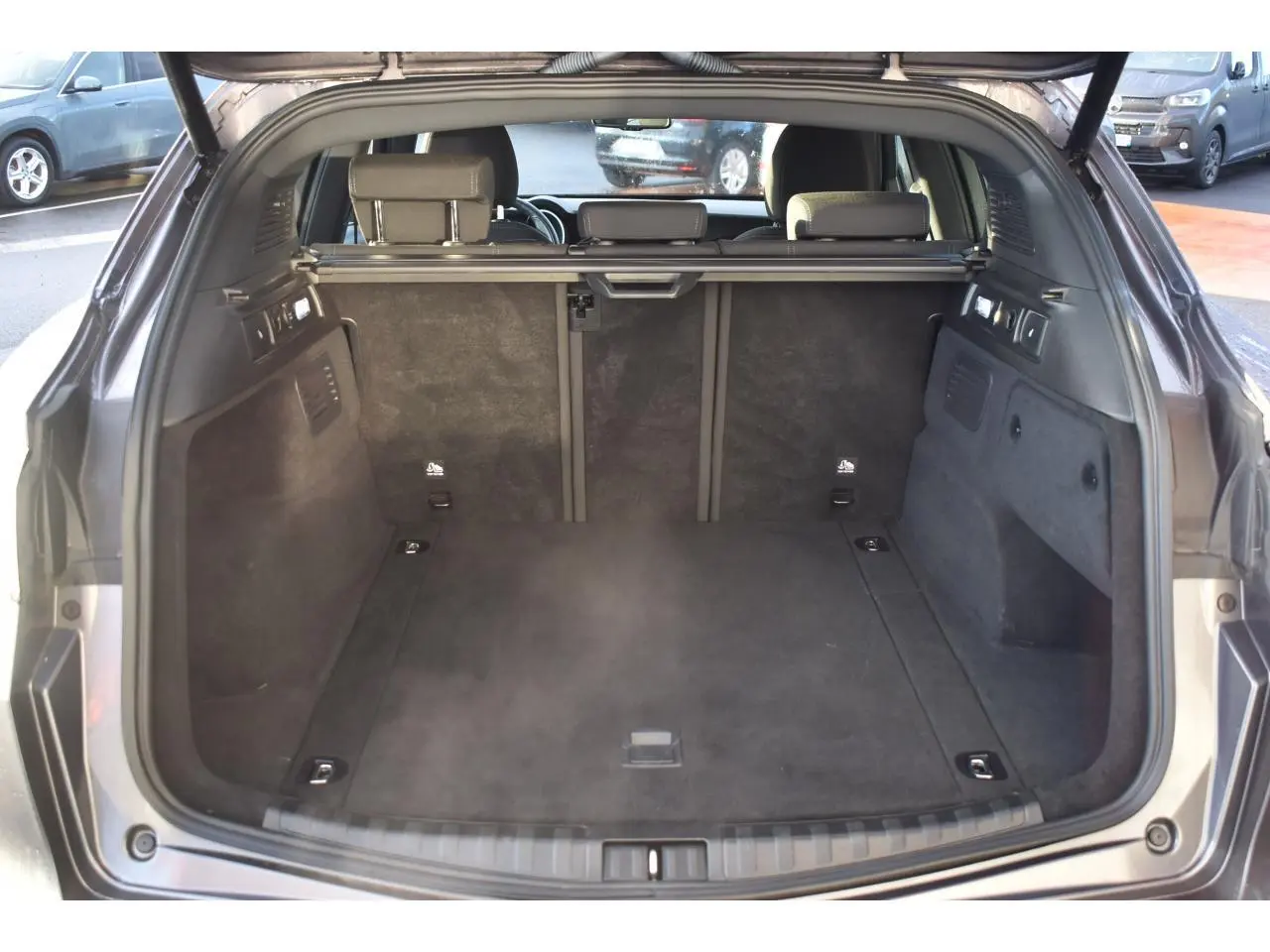 Coffre ouvert vu de l'arrière d'un Alfa Romeo Stelvio gris Vesuvio, montrant l'espace de chargement et les dossiers arrière.