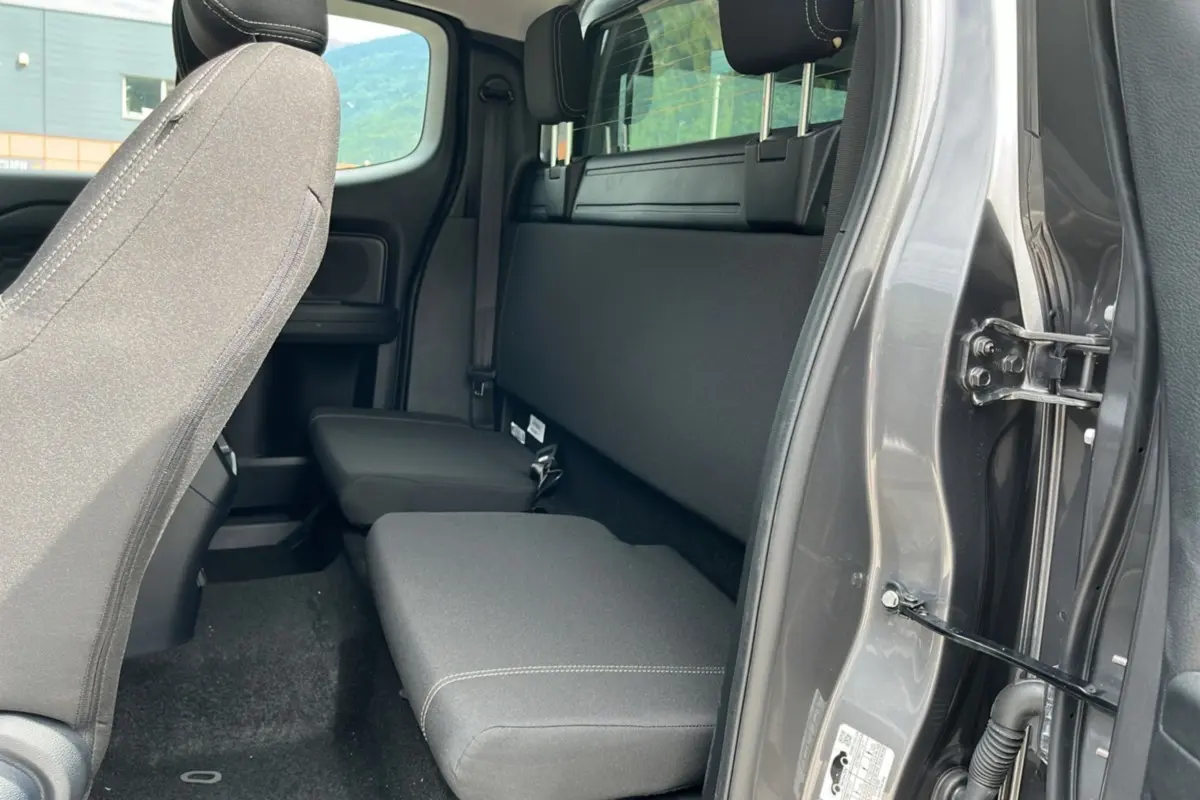 Vue intérieure côté droit du Ford Ranger gris carbone 2025, montrant la banquette arrière Supercab et l'ouverture de porte.