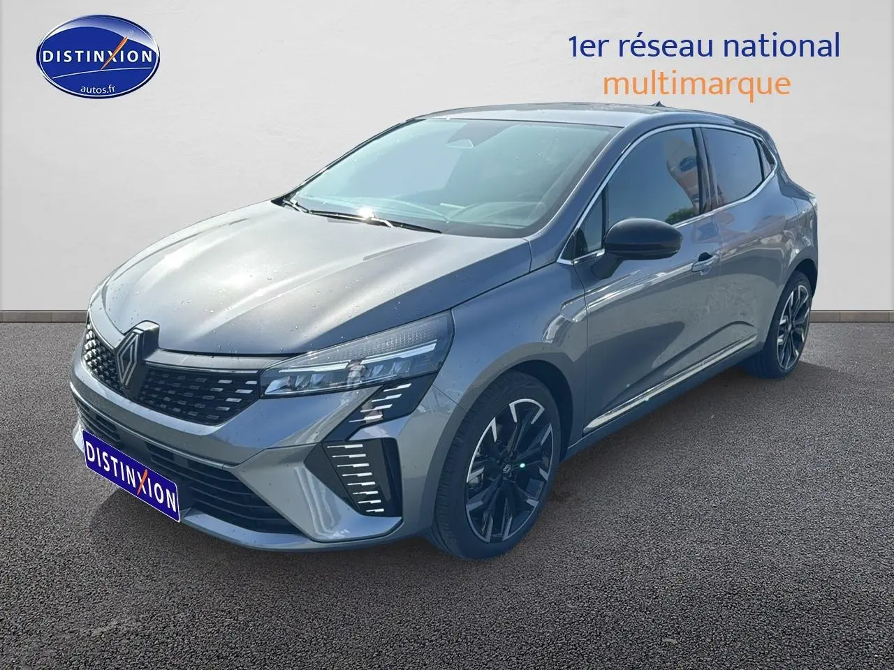 Renault Clio V gris schiste vue 3/4 avant droit avec calandre chromée et jantes alu noires.