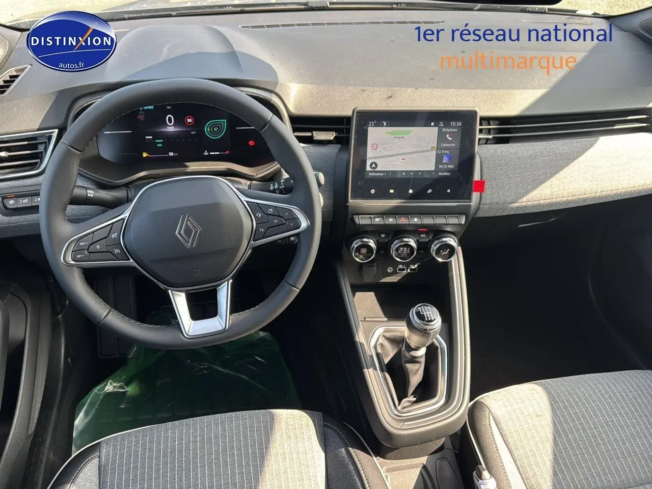 Vue intérieure avant de la Renault Clio V 1.0 TCe 90 Techno, tableau de bord gris avec écran tactile et boîte manuelle.