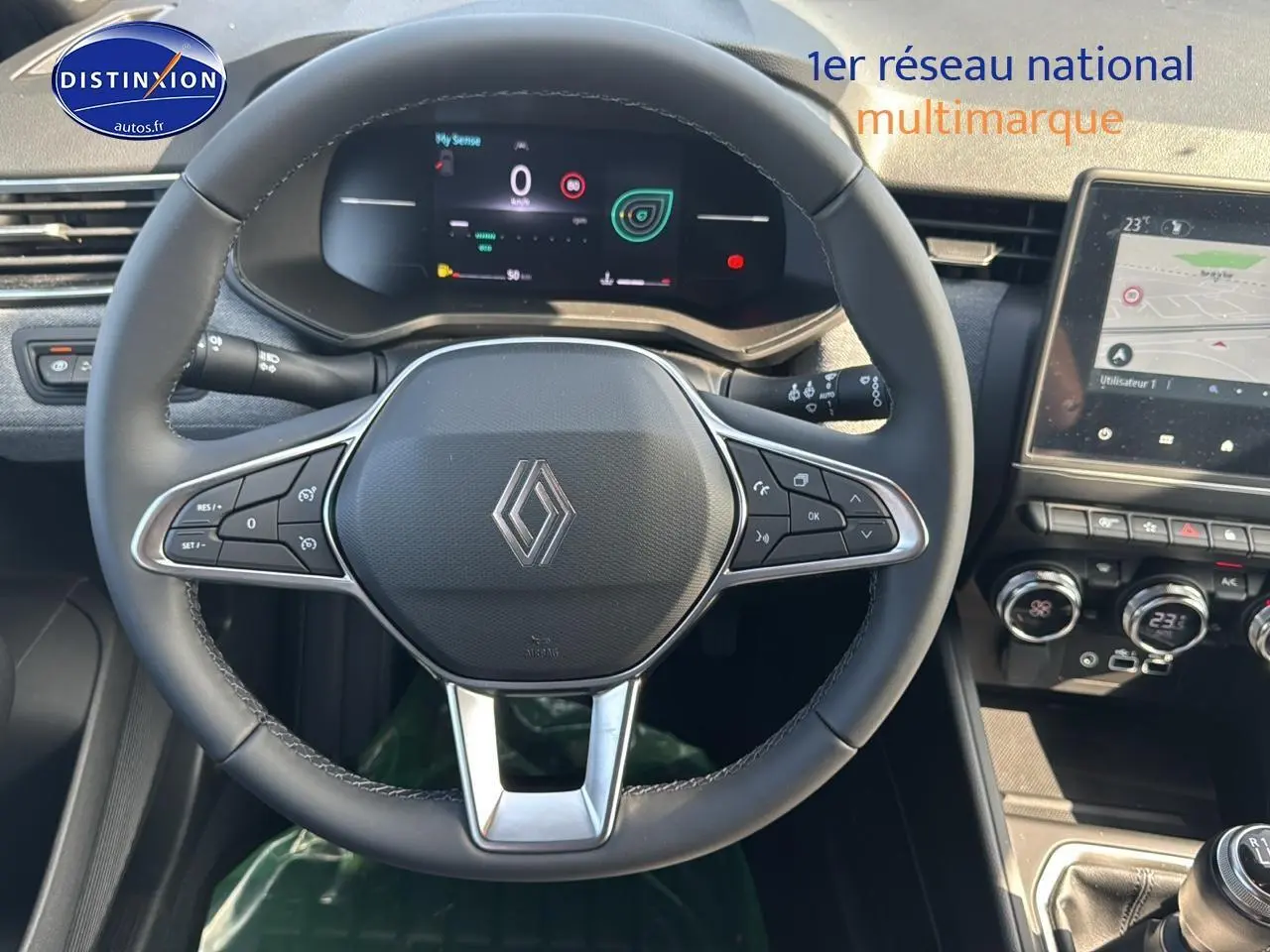 Vue intérieure centrée sur le volant multifonction noir de la Renault Clio V avec tableau de bord numérique et écran tactile.