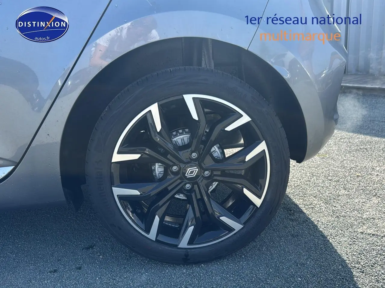 Gros plan sur la jante alu noire et argentée du côté arrière droit d'une Renault Clio V gris schiste.