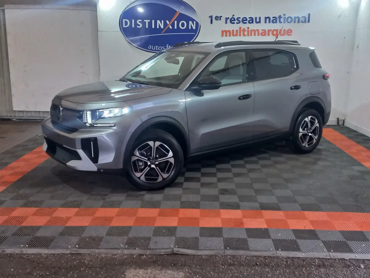 Vue 3/4 avant droit d'un SUV Citroën C3 gris foncé avec jantes noires et détails modernes sur fond intérieur showroom.