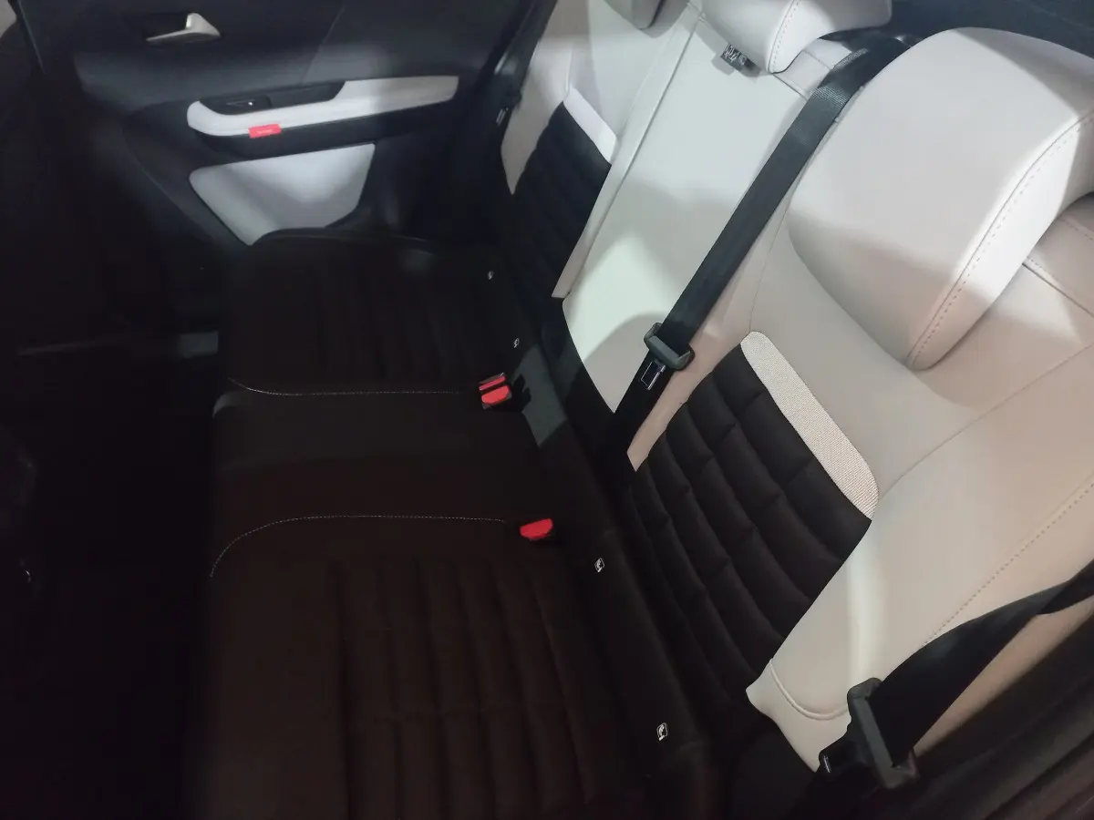 Vue intérieure des sièges arrière bicolores noir et beige de la Citroën C3 hybride 2025, avec ceintures de sécurité visibles.
