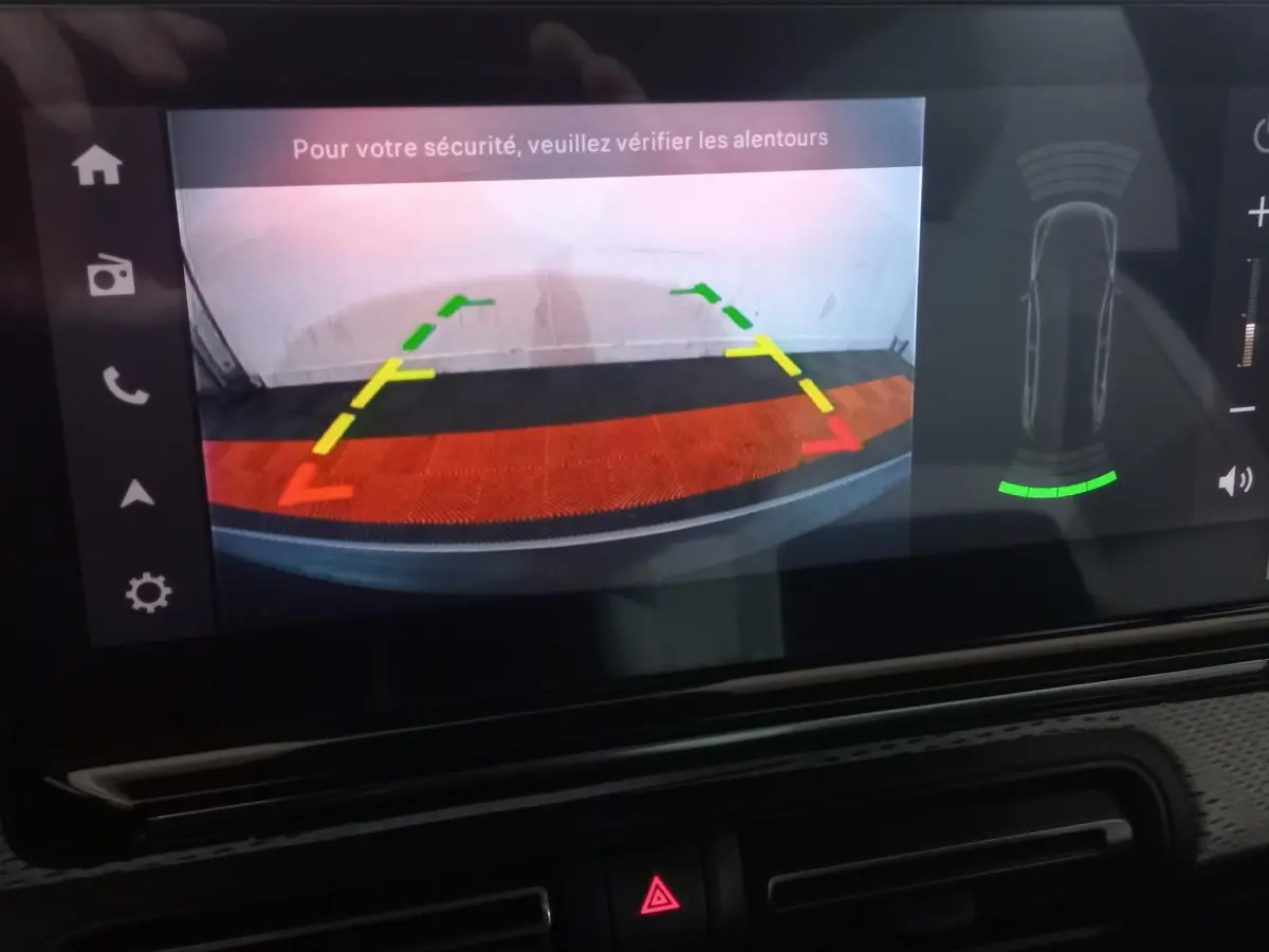 Écran tactile de la Citroën C3 hybride 2025 affichant la caméra de recul avec guidage coloré et alertes de sécurité.