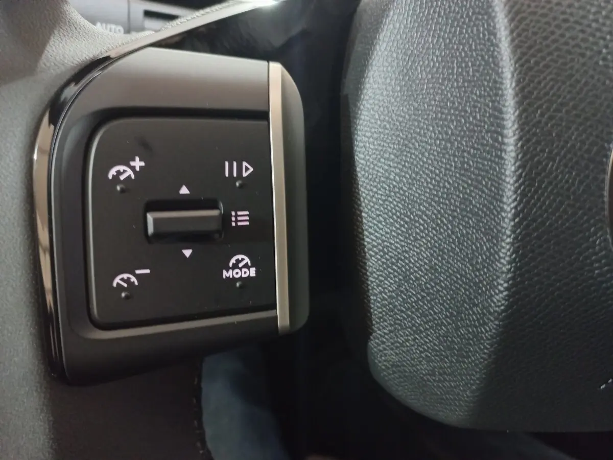Gros plan sur les commandes de régulateur de vitesse au volant cuir gris foncé d'une Citroën C3 hybride 2025.