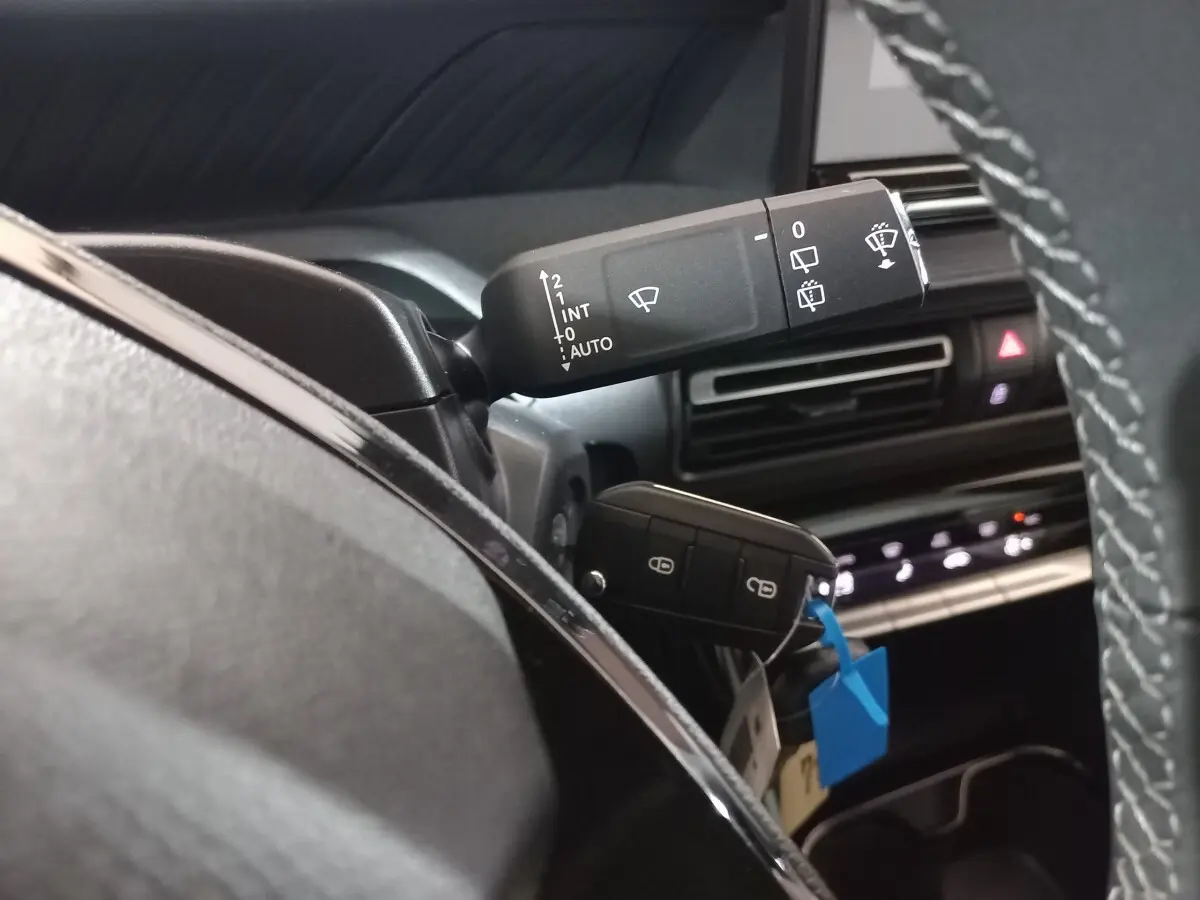 Gros plan intérieur sur la commande d'essuie-glace et clé dans le contact d'une Citroën C3 hybride 2025, tableau de bord noir.