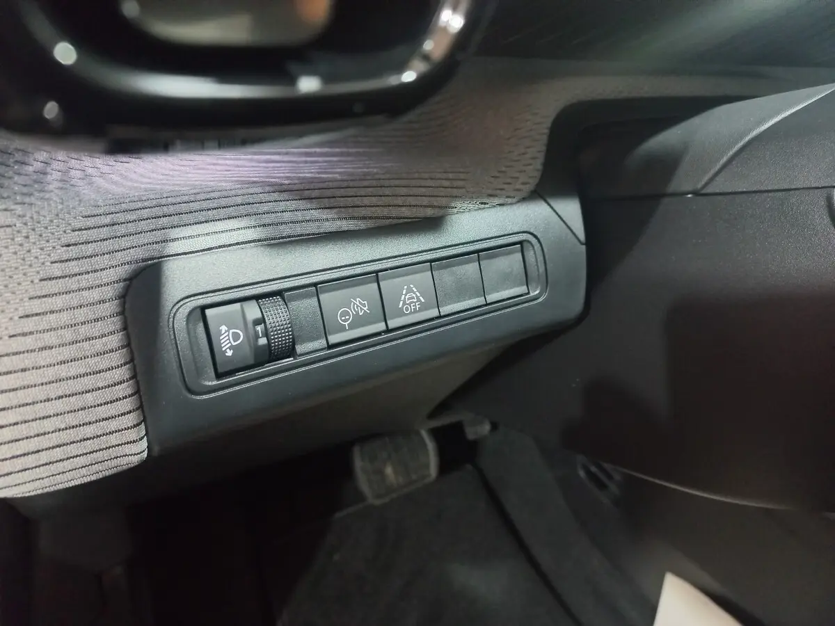 Gros plan sur les commandes d’aide à la conduite à gauche du volant dans l’habitacle gris foncé du Citroën C3 hybride 2025.