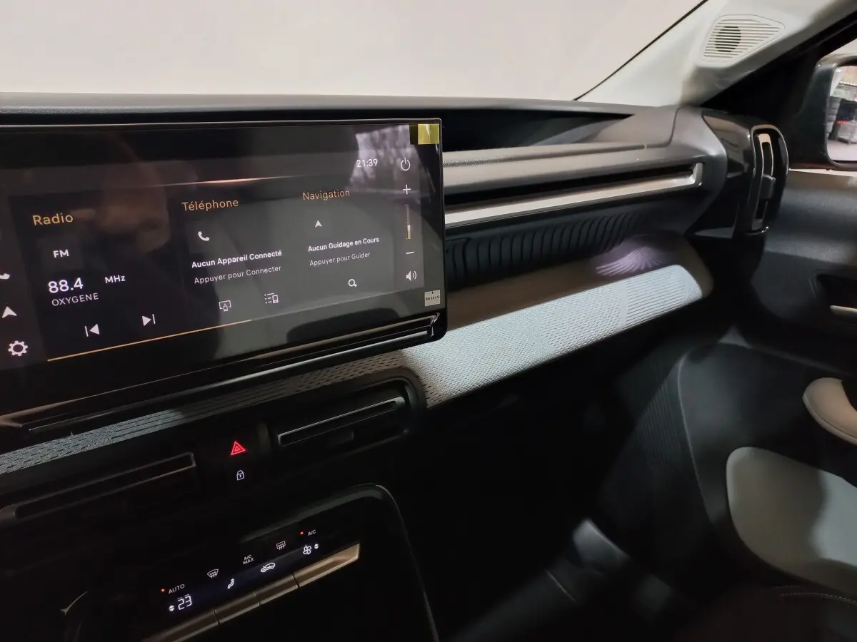 Vue intérieure côté passager du tableau de bord gris foncé de la Citroën C3 hybride avec écran tactile central lumineux.