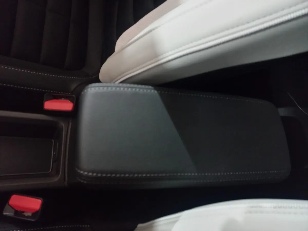 Détail de l'accoudoir central noir entre les sièges avant clair dans l'habitacle d'une Citroën C3 hybride 2025.