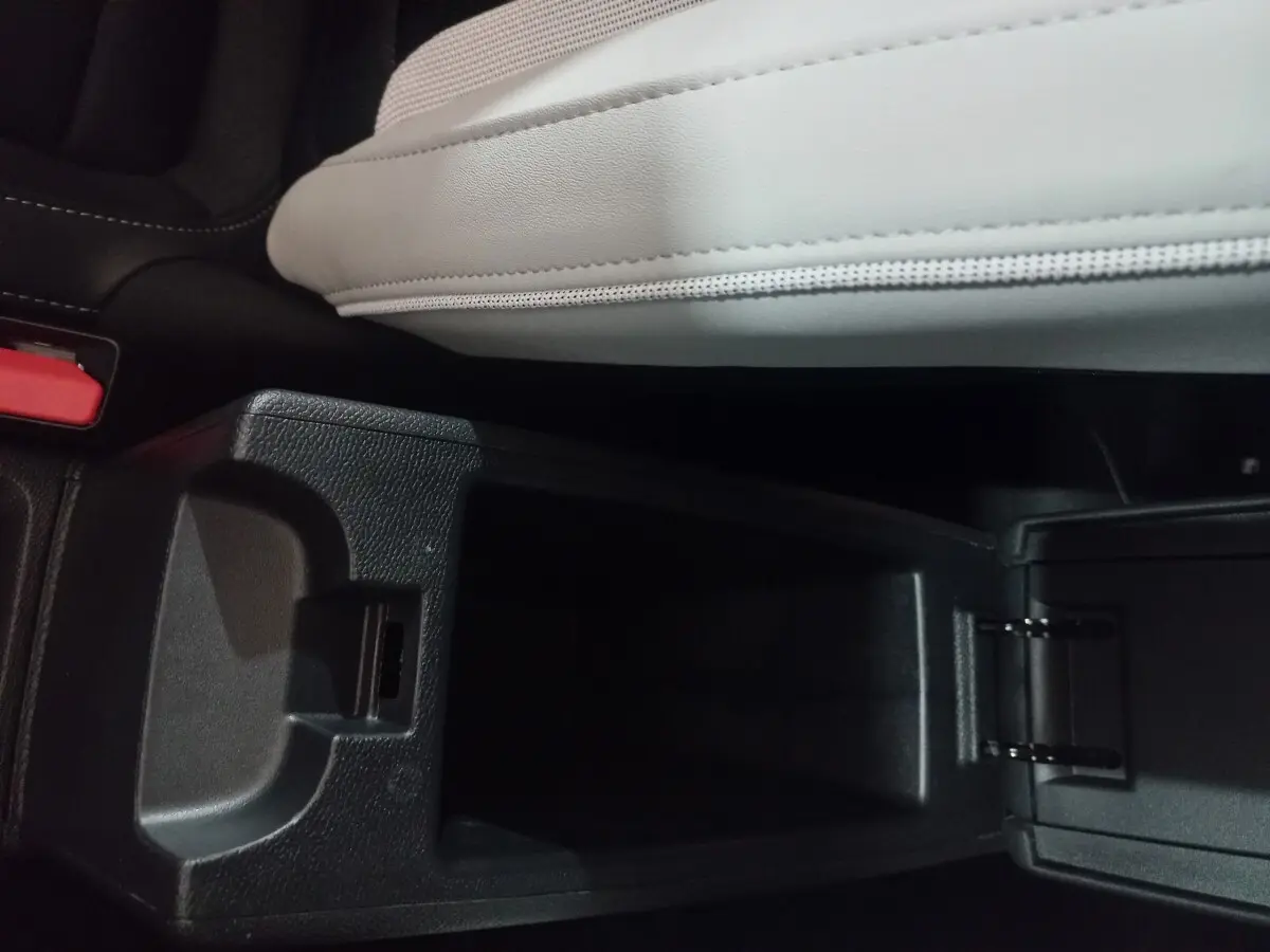 Vue en plongée sur la console centrale ouverte avec accoudoir gris clair de la Citroën C3 hybride 2025.