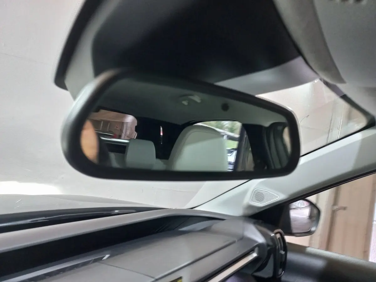 Vue intérieure du rétroviseur central d’une Citroën C3 hybride gris foncé, avec sièges arrière visibles en reflet.