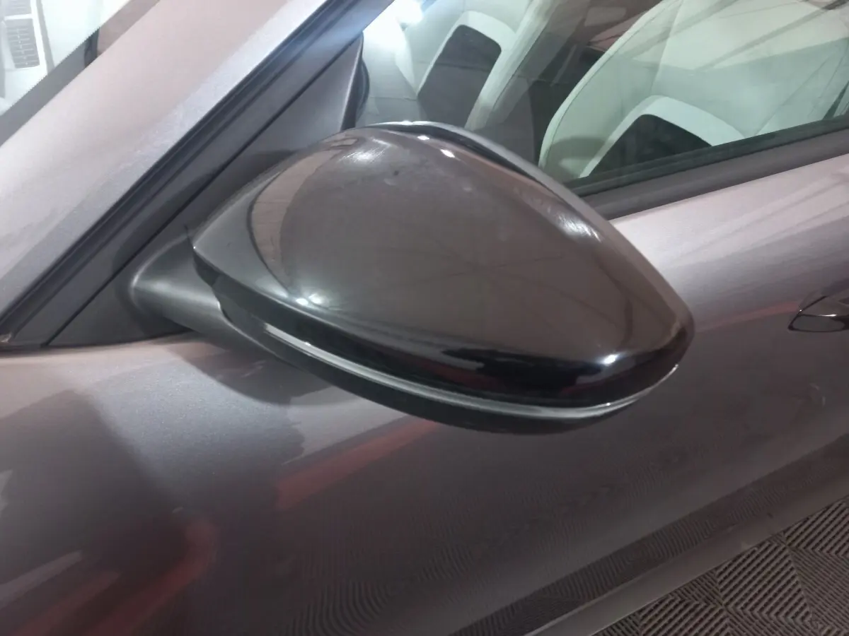 Rétroviseur côté gauche noir brillant de la Citroën C3 hybride gris foncé, vue rapprochée sur la portière avant.