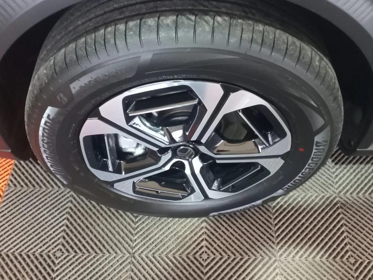 Gros plan sur la roue avant droite de la Citroën C3 hybride 2025, jante bicolore noir et argent, pneu Bridgestone.