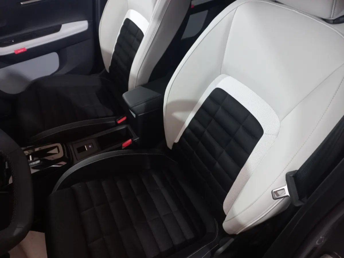 Vue intérieure rapprochée des sièges avant bicolores noir et blanc de la Citroën C3 Hybride 2025.