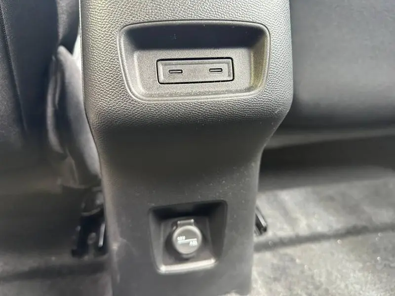 Détail de la console arrière avec ports USB et prise 12V dans une Citroën C3 électrique Noir Perla Nera, vue intérieure.