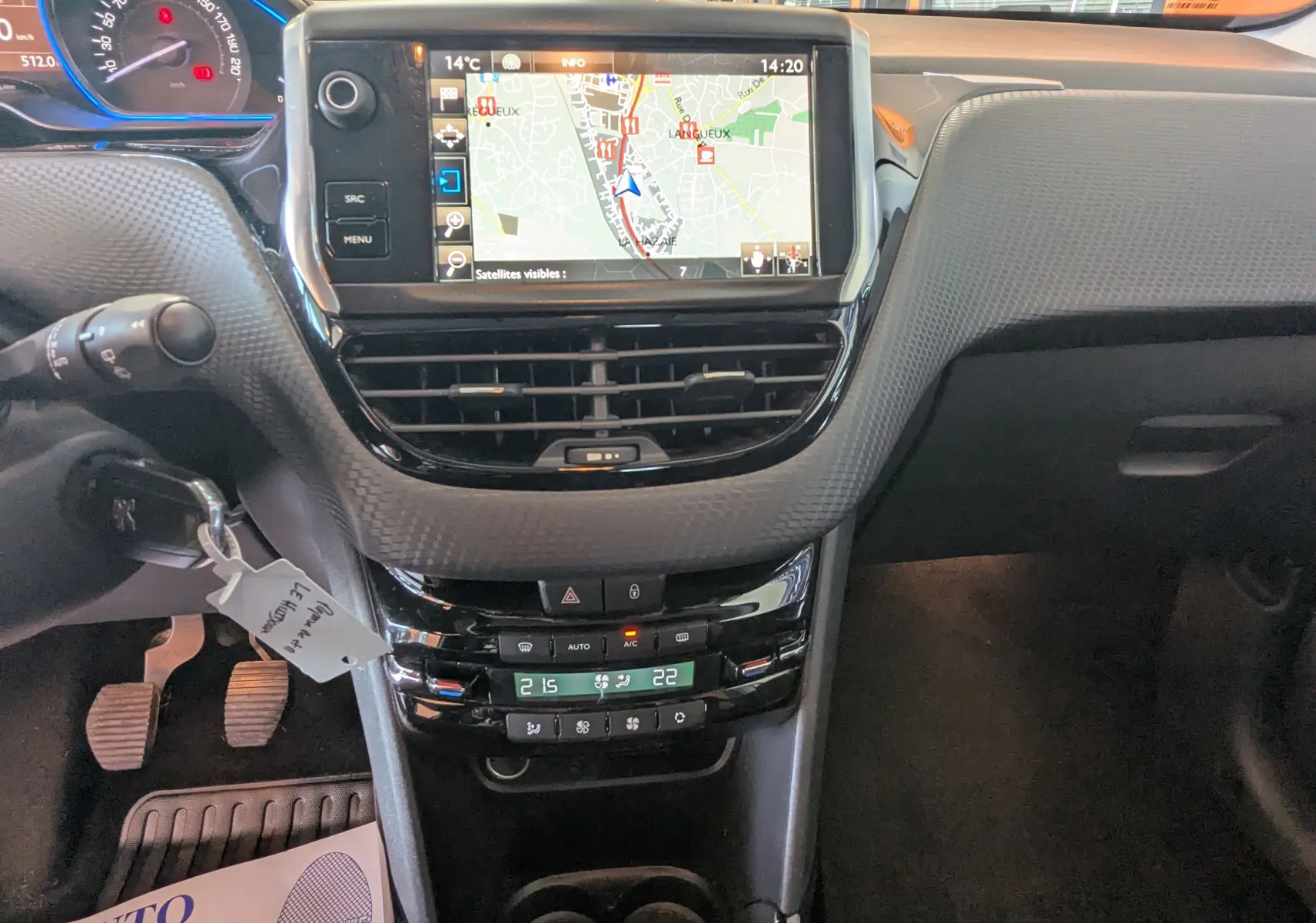 Vue intérieure centrée sur la console centrale du Peugeot 2008 gris, avec écran GPS et commandes de climatisation visibles.