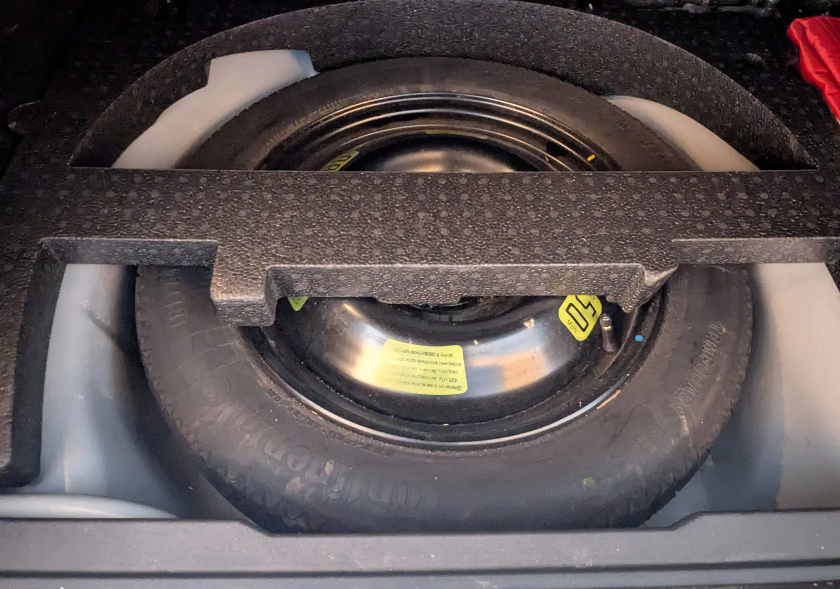 Vue rapprochée de la roue de secours noire logée dans le coffre d'une Peugeot 2008 gris Artense de 2015.