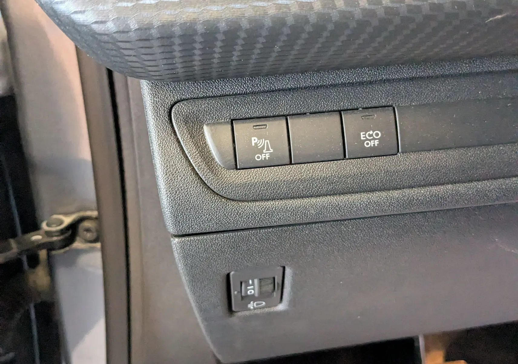 Gros plan sur les commandes de tableau de bord côté gauche du Peugeot 2008 gris Artense, avec boutons de parking et mode ECO.