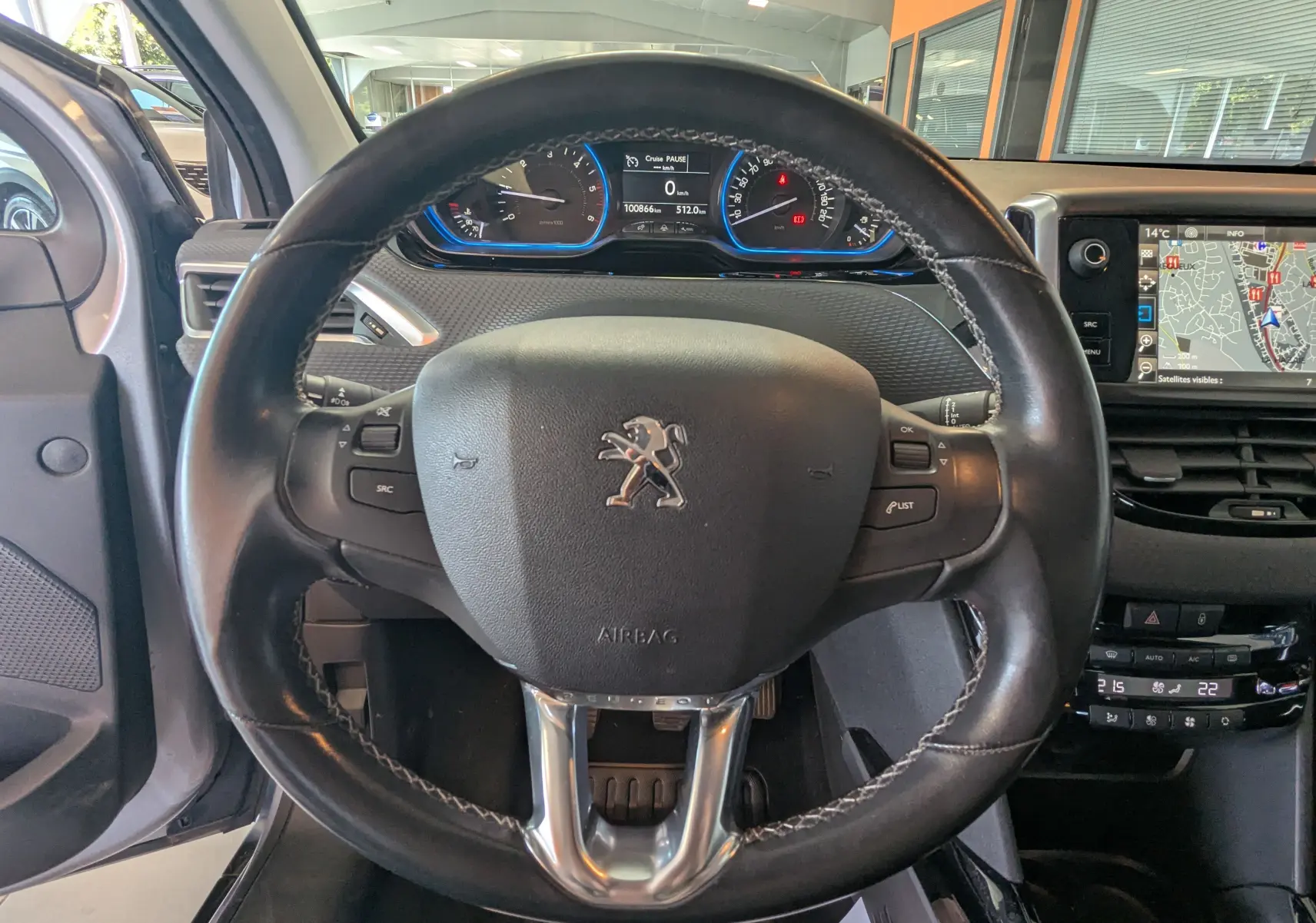 Vue centrée sur le volant cuir du Peugeot 2008 gris Artense, avec tableau de bord et écran GPS visibles.