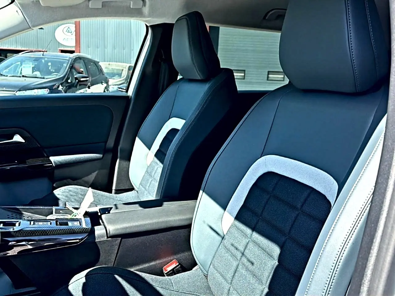 Vue intérieure sur les sièges avant gris et noirs du Citroën C5 Aircross avec accoudoir central et porte-gobelets.