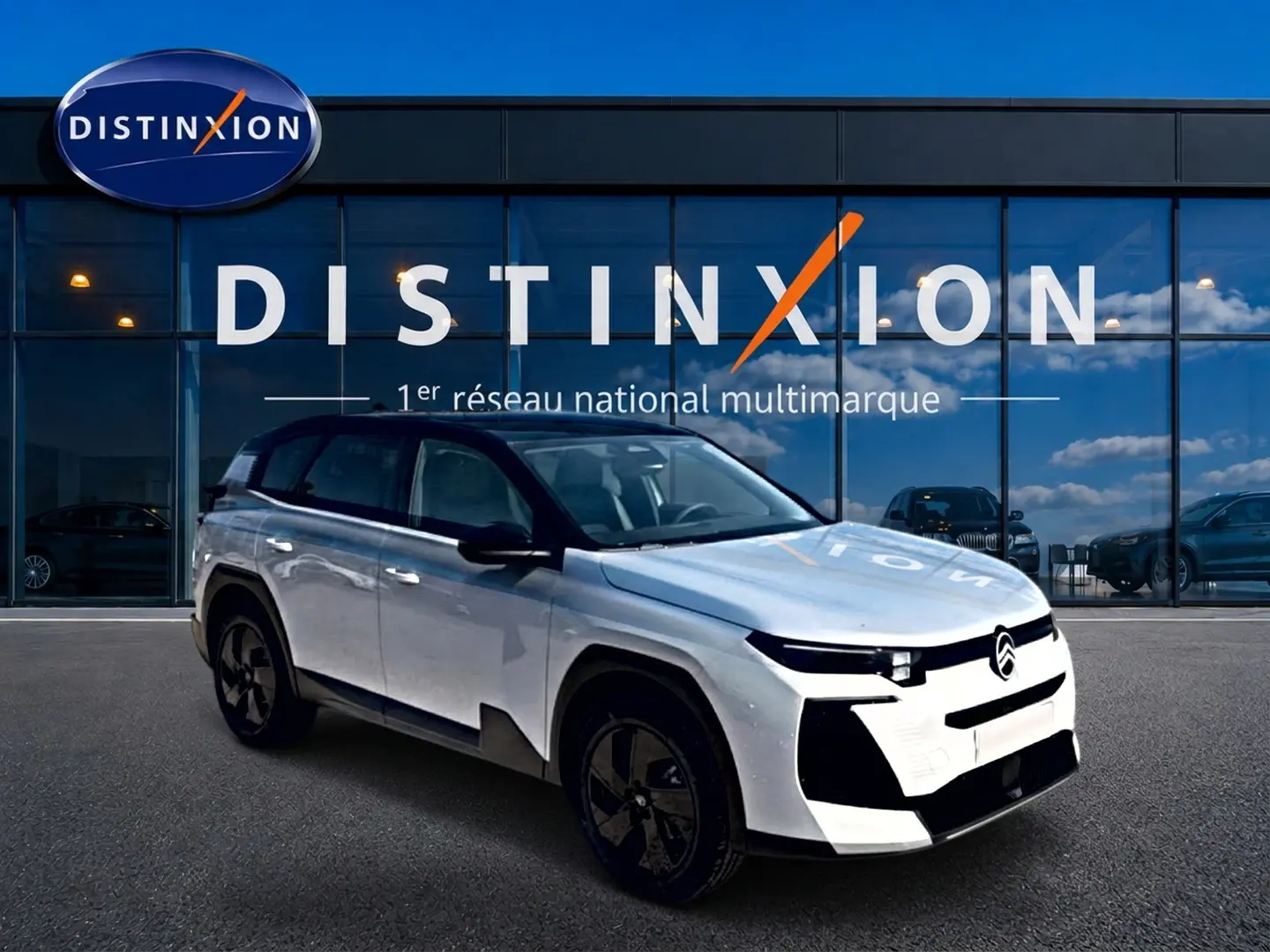 Vue 3/4 avant du Citroën C5 Aircross hybride blanc avec toit noir et jantes alliage noires devant une vitrine Distinxion.