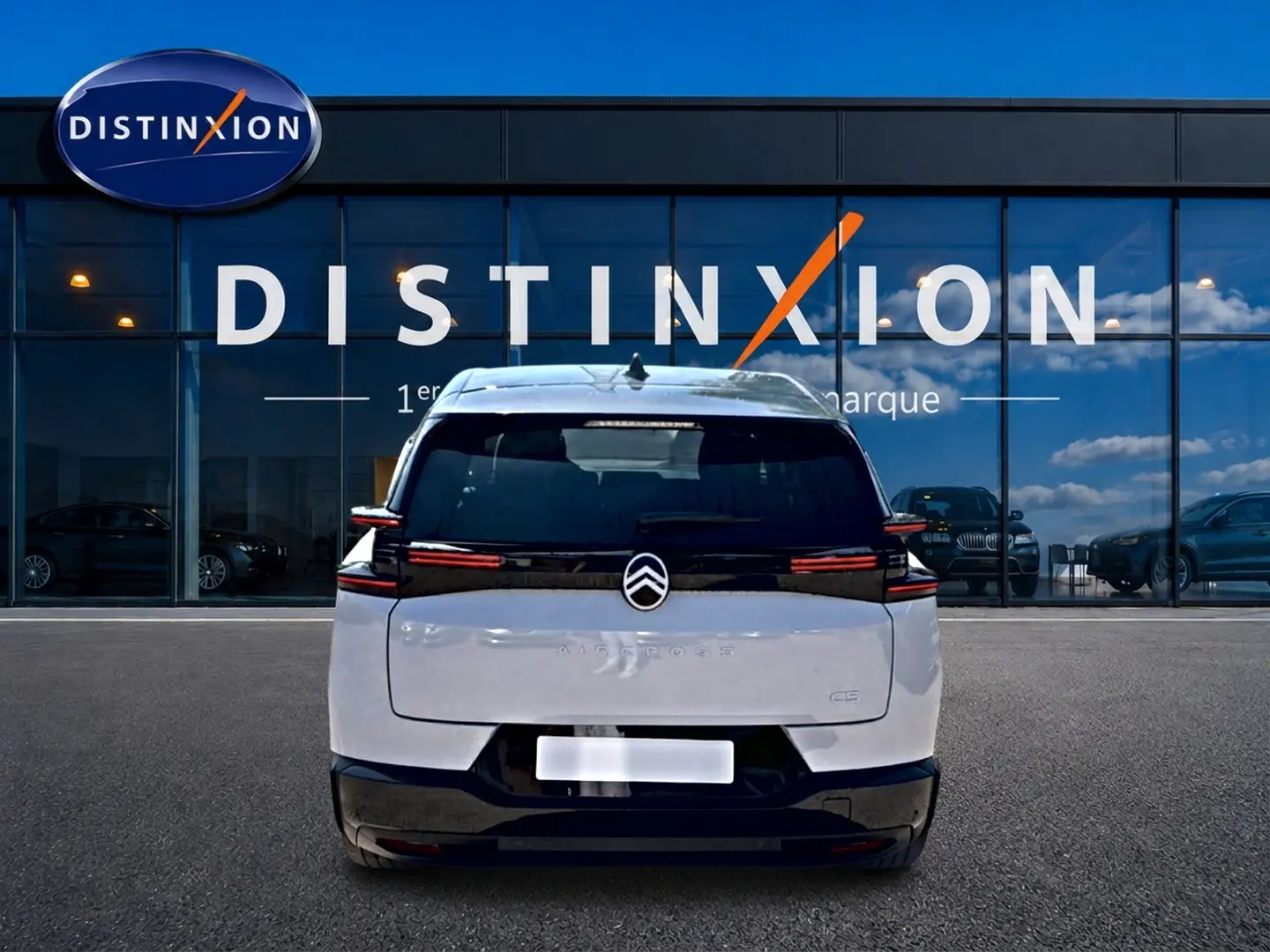 Vue arrière d'un Citroën C5 Aircross blanc et noir avec feux arrière LED, stationné devant une vitrine Distinxion.