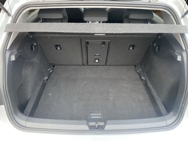 Coffre ouvert vu de l'arrière d'une Volkswagen Golf VIII gris argent, montrant un espace de chargement propre et spacieux.