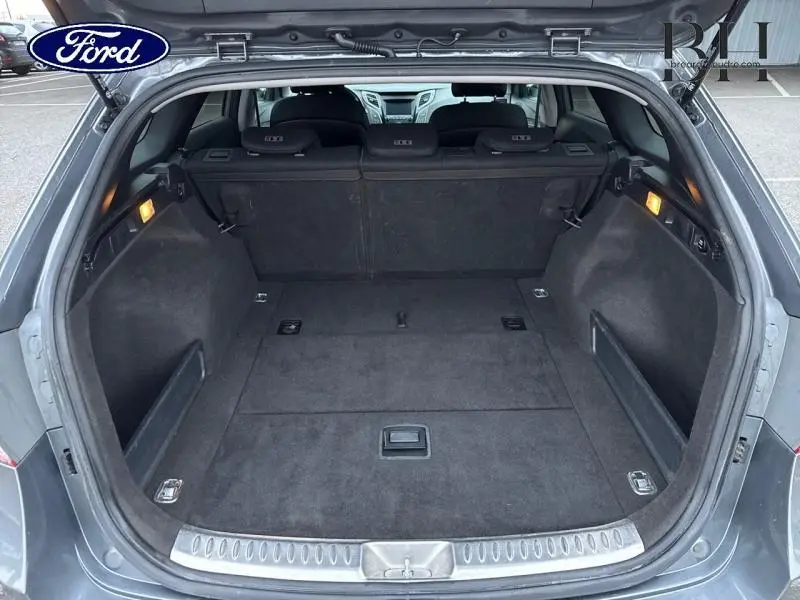 Coffre ouvert vu de l'arrière d'une Hyundai i40 SW Sleek Silver, espace de chargement propre et bien éclairé.