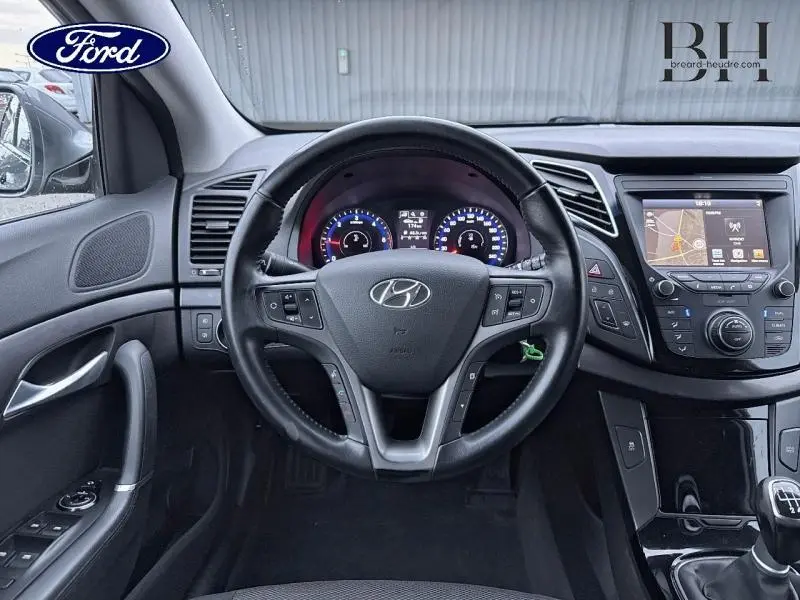 Vue intérieure centrée sur le volant cuir de la Hyundai i40 SW 2017 avec tableau de bord et écran tactile visibles