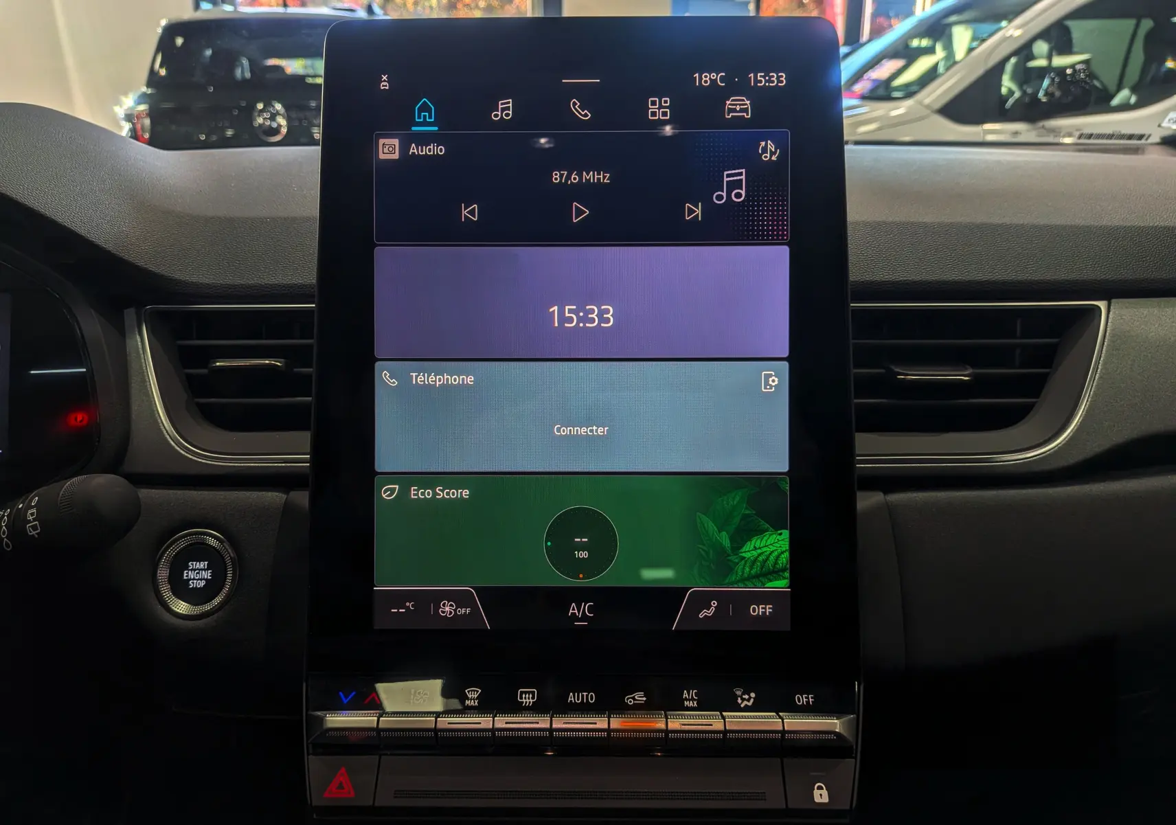Écran tactile central du tableau de bord du Renault Captur E-TECH 2025 avec commandes climatisation et bouton start/stop visible.