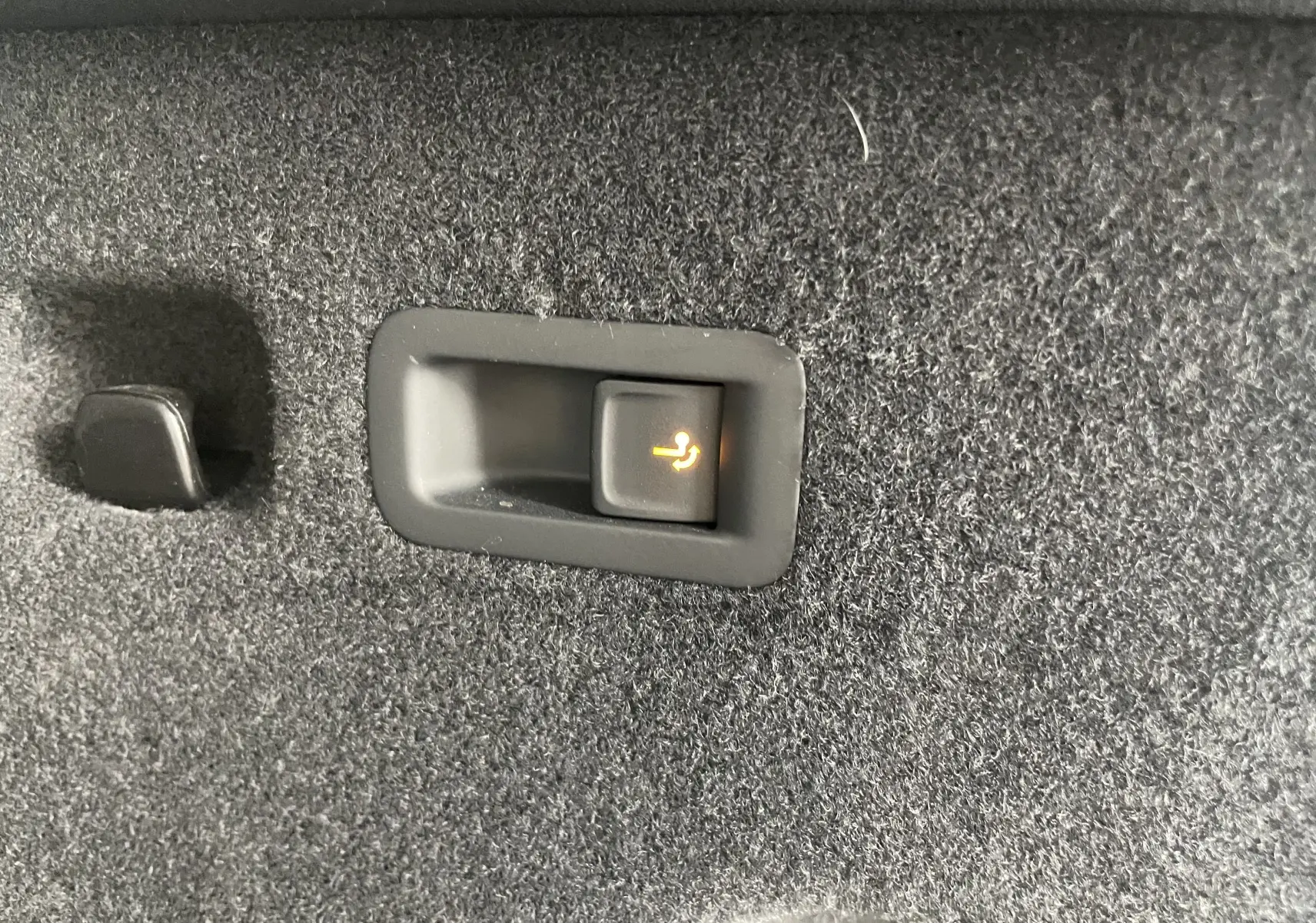 Bouton de rabattement électrique des sièges dans le coffre du Skoda Kodiaq noir métal 2024, version 7 places.