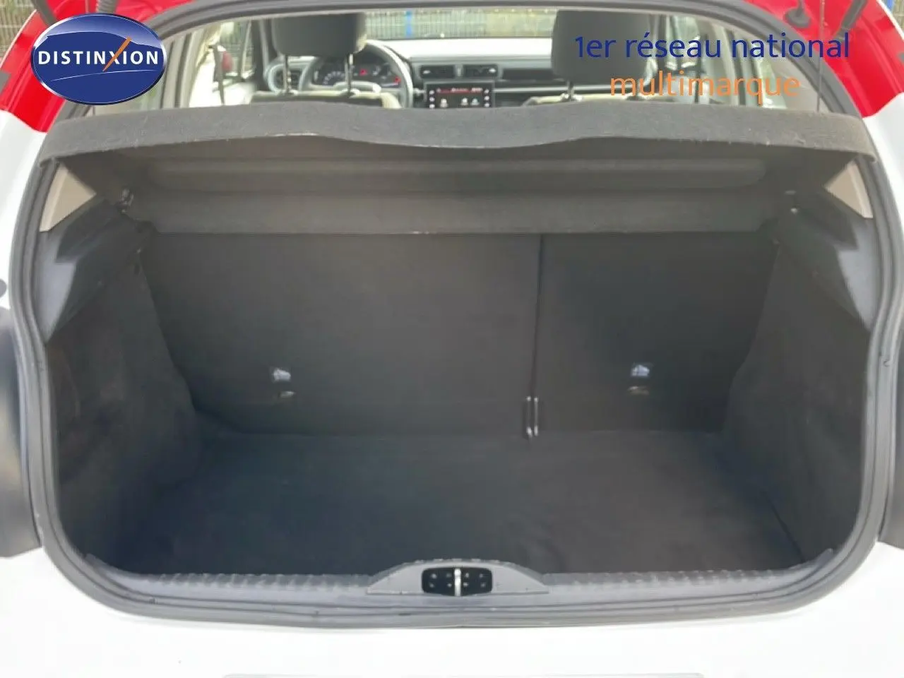 Coffre ouvert d’une Citroën C3 blanche avec toit rouge, vue arrière montrant l’espace de chargement vide.