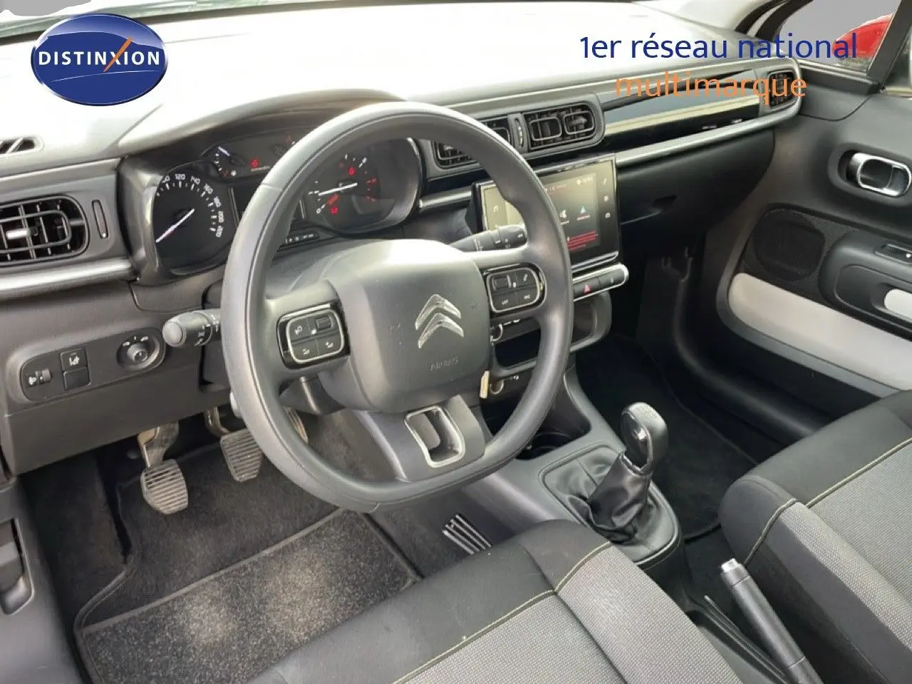 Vue intérieure côté conducteur de la Citroën C3 2018, tableau de bord noir avec volant multifonction et boîte manuelle.