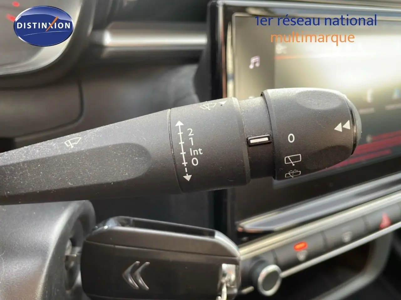 Gros plan sur la commande d'essuie-glace noire dans l'habitacle d'une Citroën C3 blanche au toit rouge.